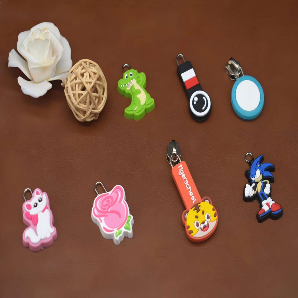 Detailed close-up of custom-shaped PVC clothing bags hanging pendant and zipper pull accessories.